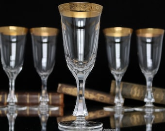 May include: Set of six clear glass wine glasses with gold rims. The glasses have a delicate, elegant design and are perfect for serving wine or other beverages.