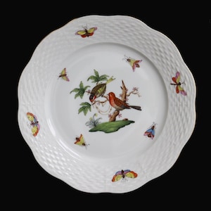 May include: White decorative plate with a scalloped edge and a woven texture. The center features a detailed illustration of two birds perched on a branch, surrounded by colorful butterflies. The rim is trimmed with gold.