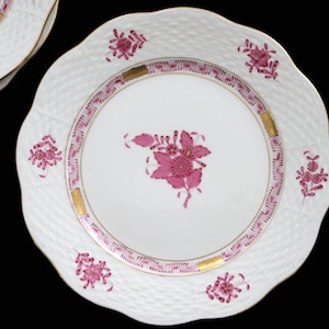 以下が含まれることがあります： 白磁の皿で、スカラップエッジとテクスチャードバスケット織りの模様が特徴です。 皿は、中央と縁にピンクの花柄のデザインがあり、金色のアクセントが付いています。 皿は食べ物を提供するように設計されています。