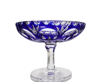 May include: A blue and clear glass pedestal bowl with a cut glass design. The bowl is on a white background.