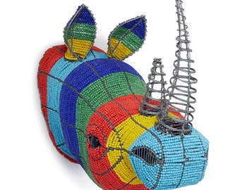 May include: A colorful beaded rhinoceros head wall sculpture with a wire horn. The sculpture is made of blue, green, yellow, red, and black beads.