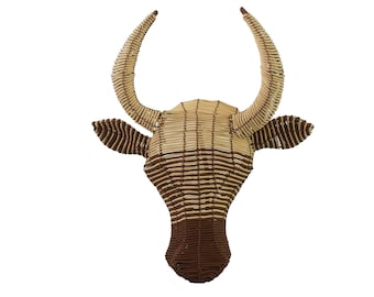 May include: A brown and tan woven bull head wall decor. The bull head is made of woven strips of material and has a 3D effect.