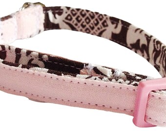 May include: A pet collar featuring a brown and cream elephant pattern on the inner side and a solid light pink fabric on the outer side. The collar includes a light pink plastic side-release buckle and a matching light pink plastic adjustment slider.