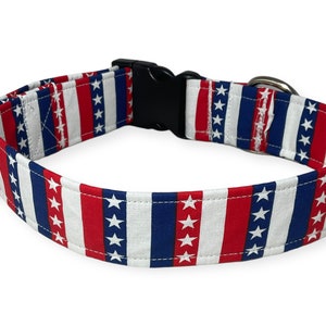 May include: A red, white, and blue dog collar with a stars and stripes pattern. The collar has a black plastic buckle and a silver metal D-ring.