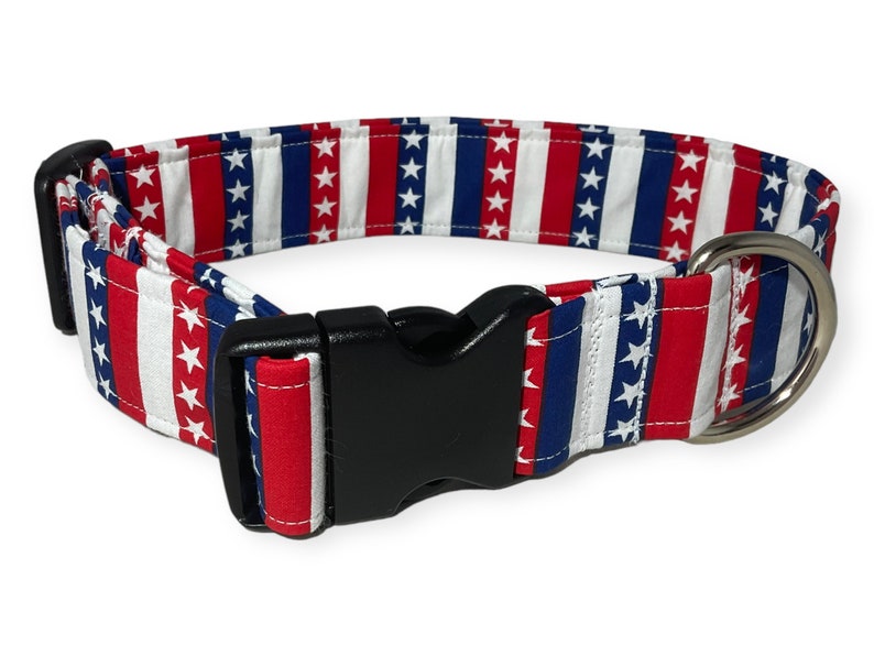 May include: Red, white, and blue striped dog collar with white stars. The collar has a black plastic buckle and a silver D-ring.