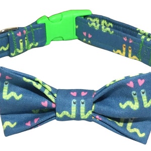 May include: A blue dog collar with a green buckle and a matching bow tie. The collar and bow tie feature a pattern of green worms with pink hearts.