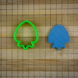 Könnte beinhalten: Zwei Ausstecher, einer grün und einer blau, in Form eines Pilzes auf einem Bambus-Schneidebrett.