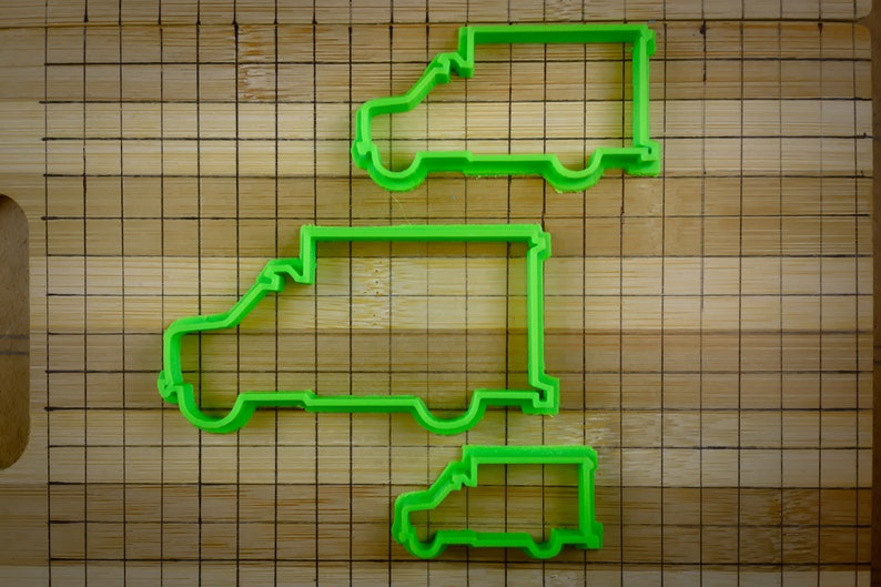 May include: Three green plastic cookie cutters shaped like delivery vans of different sizes.