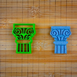 May include: Two cookie cutters shaped like ancient Greek columns. The cutter on the left is green and the cutter on the right is blue.