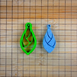May include: Two decorative ornaments, one green and one blue, with a geometric design. The ornaments are on a wooden surface.