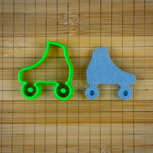 Peut inclure: Deux emportes-pièces en forme de patins à roulettes, l'un vert et l'autre bleu, sur une surface en bambou.