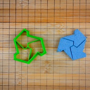 May include: A green plastic cookie cutter and a blue cookie in the shape of a five-pointed star.