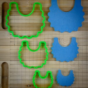 K&ouml;nnte beinhalten: Vier Ausstecher in verschiedenen Gr&ouml;&szlig;en, zwei sind gr&uuml;n und zwei sind blau. Die Ausstecher sind bib-f&ouml;rmig mit gewellten R&auml;ndern.