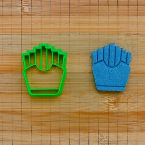 Könnte beinhalten: Zwei Ausstecher, einer grün und einer blau, in Form von Pommes Frites.