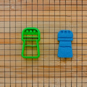 May include: Two salt and pepper shakers, one green and one blue, on a wooden surface.
