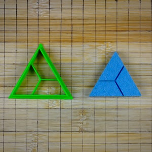 May include: Two triangle-shaped puzzle pieces, one green and one blue, on a bamboo surface.