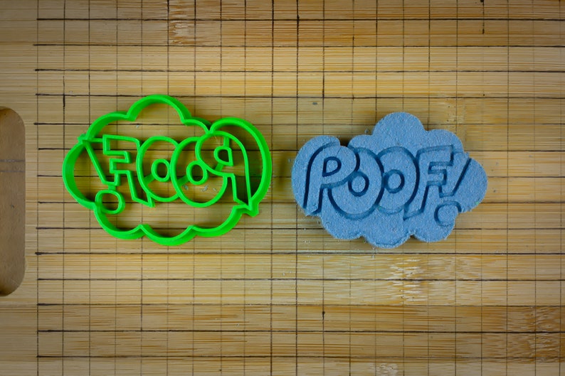 May include: Two cookie cutters, one green and one blue, shaped like speech bubbles with the words "FOOSH" and "POOF" inside.