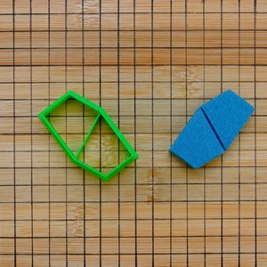 Könnte beinhalten: Zwei Plastik-Ausstecher auf einem Holzbrett. Ein Ausstecher ist grün und hat die Form eines Sechsecks. Der andere Ausstecher ist blau und hat die Form einer Mondsichel.