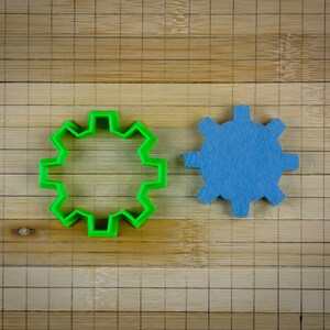 Peut inclure: Deux engrenages, l'un vert et l'autre bleu, sur une surface en bois.