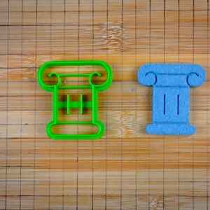May include: Two cookie cutters shaped like columns. One is green plastic and the other is blue.