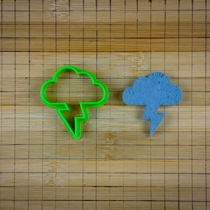 May include: Two cookie cutters, one green and one blue, shaped like a cloud with a lightning bolt underneath.