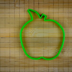 Peut inclure: Emporte-pi&egrave;ce en forme de pomme en plastique vert sur une surface en bois.
