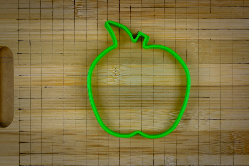 Peut inclure: Emporte-pi&egrave;ce en forme de pomme en plastique vert sur une surface en bois.