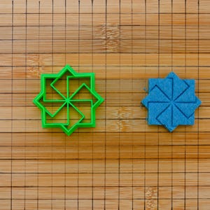 Può includere: Due formine per biscotti geometriche, una verde brillante e una blu solida, su un tagliere di bambù. Le forme hanno un design a forma di stella. Il tagliere ha un motivo a griglia. Ideale per la cottura o l'artigianato.