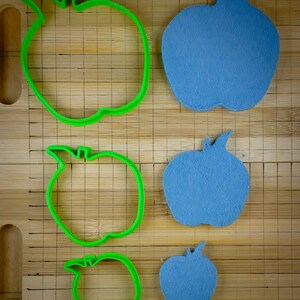 Peut inclure: Quatre emportes-pi&egrave;ces en forme de pomme, deux verts et deux bleus. Les emportes-pi&egrave;ces verts sont plus grands que les bleus.
