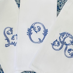 May include: Three white kitchen towels with blue embroidered letters "L", "O", and "V" in a decorative script font.
