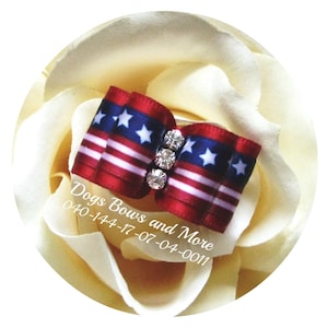 May include: A red, white, and blue bow with white stars and rhinestones. The bow is on a white background with the text "Dogs Bows and More 040-144-17-07-04-0011".