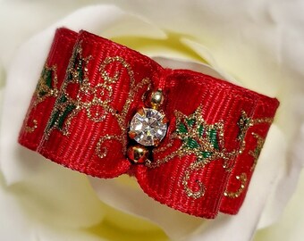 May include: A red ribbon bow with gold and green accents and a clear rhinestone in the center.