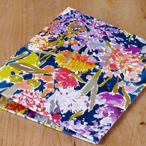 May include: A blue binder with a floral pattern in shades of pink, yellow, purple, and white. The flowers are abstract and painted in a watercolour style.