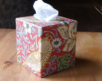 May include: A red tissue box cover with a floral and bird pattern. The cover features a repeating pattern of stylized flowers, leaves, and birds in shades of red, green, blue, and yellow.