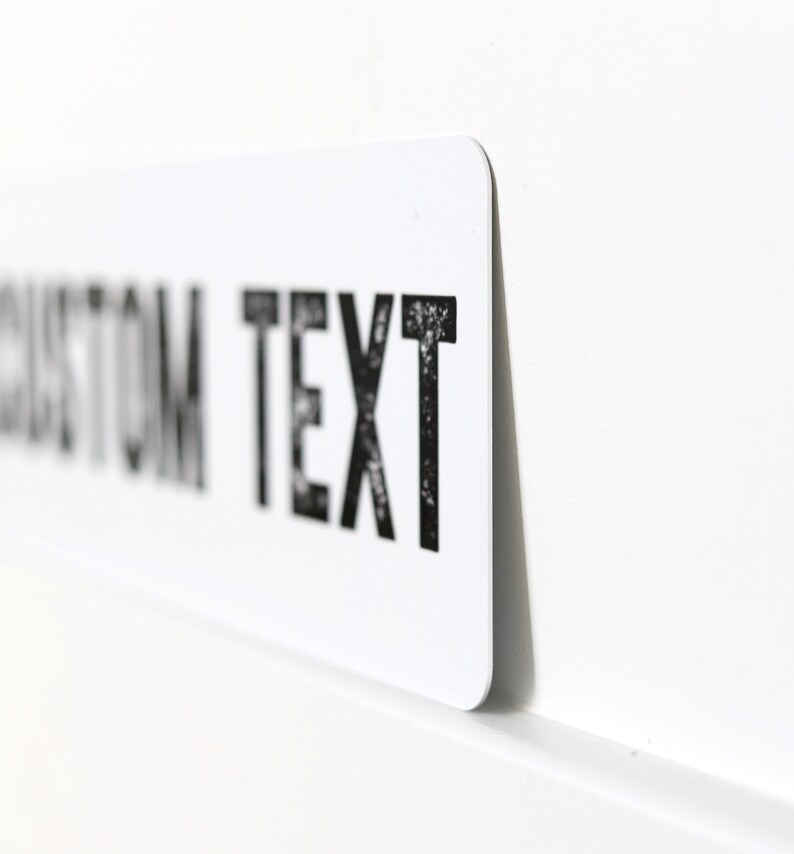 Op de afbeelding: Een wit rechthoekig bord met zwarte tekst die "CUSTOM TEXT" luidt.