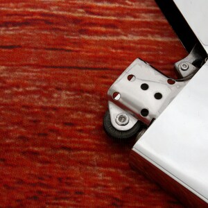 Puede incluir: Un encendedor plateado con una superficie texturizada y una rueda en el lateral. El encendedor est&aacute; abierto y la tapa est&aacute; volteada hacia atr&aacute;s.