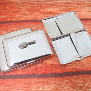 May include: Two silver cigarette cases, one with a small silver shovel design on the lid.