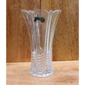 May include: A clear glass vase with a textured design and a small tractor charm attached to the top.