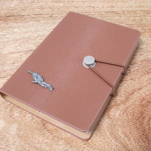May include: A brown leather-bound journal with a silver metal clasp and a decorative metal scuba diver on the front cover.