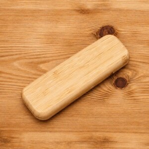 K&ouml;nnte beinhalten: Eine rechteckige, hellfarbene Holzkiste mit abgerundeten Kanten. Die Kiste ist aus Bambus gefertigt und hat ein nat&uuml;rliches Holzmaserungsmuster. Die Kiste ist leer und eignet sich zur Aufbewahrung kleiner Gegenst&auml;nde.