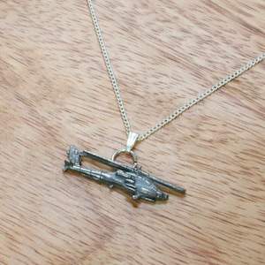 Könnte beinhalten: Eine silberne Kettenkette mit einem silbernen Hubschrauber-Anhänger.