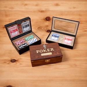 Könnte beinhalten: Ein Poker-Set aus Holz mit dunkelbraunem Finish, mit einer Box mit dem eingravierten Wort "POKER" auf der Oberseite. Das Set enthält Spielkarten, Würfel und Pokerchips in verschiedenen Farben, die alle ordentlich in schwarzen Boxen angeordnet sind.