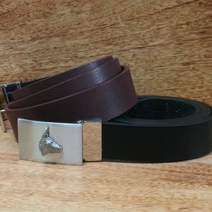 Puede incluir: Dos cinturones de cuero con una hebilla plateada con un diseño de cabeza de burro. El cinturón superior es marrón y el cinturón inferior es negro.