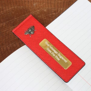 May include: Red leather bookmark with a silver bee charm and a gold plate that says "Your Message Engraved Here For Free".
