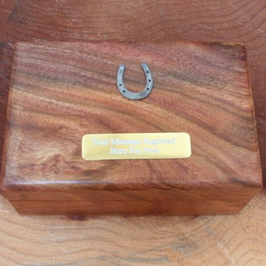 Może przedstawiać: Drewniana skrzynka z mosiężną tabliczką z napisem "Your Memories Engraved Here For You" i srebrnym podkową na górze.