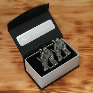 Pu&ograve; includere: Una scatola regalo nera con interno bianco, contenente due gemelli d'argento a forma di giocatori di hockey. La scatola ha l'iscrizione "Jon McCrea - Regalo inciso".