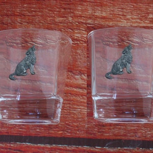 May include: Two clear glass shot glasses with a pewter wolf howling design on the front.