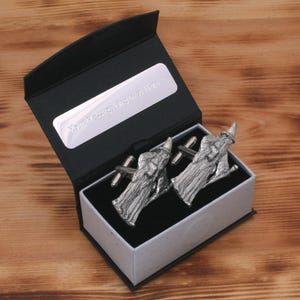 Peut inclure: Un coffret cadeau noir avec une inscription argentée qui dit "You were made for this". La boîte contient deux boutons de manchette en argent représentant un personnage de magicien.