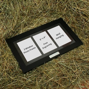 May include: Black triple photo frame with three 6x4 inch openings. The frame has a 3 window photo frame label and a free engraving label. The frame is wall hanging.
