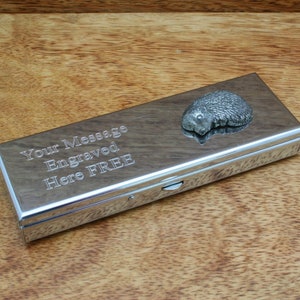 May include: A silver metal box with a hedgehog design on the lid. The box has a hinged lid and a sliding latch. The box is engraved with the text "Your Message Engraved Here FREE".